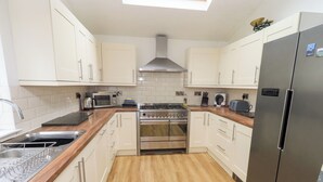 A modern kitchen with white cabinets, a stainless steel stove, and a large refrigerator. - Number Twenty (Keswick)