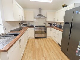 A modern kitchen with white cabinets, a stainless steel stove, and a large refrigerator.