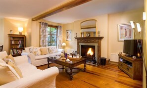 A cozy living room with a fireplace, a sofa, a coffee table, and a bookshelf. - Silver Howe (Windermere)