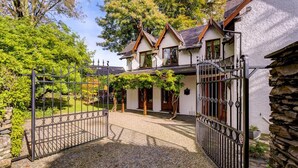 Ein traditionelles Haus mit einer Steinsäule, einer Schotterauffahrt und einem Metalltor.