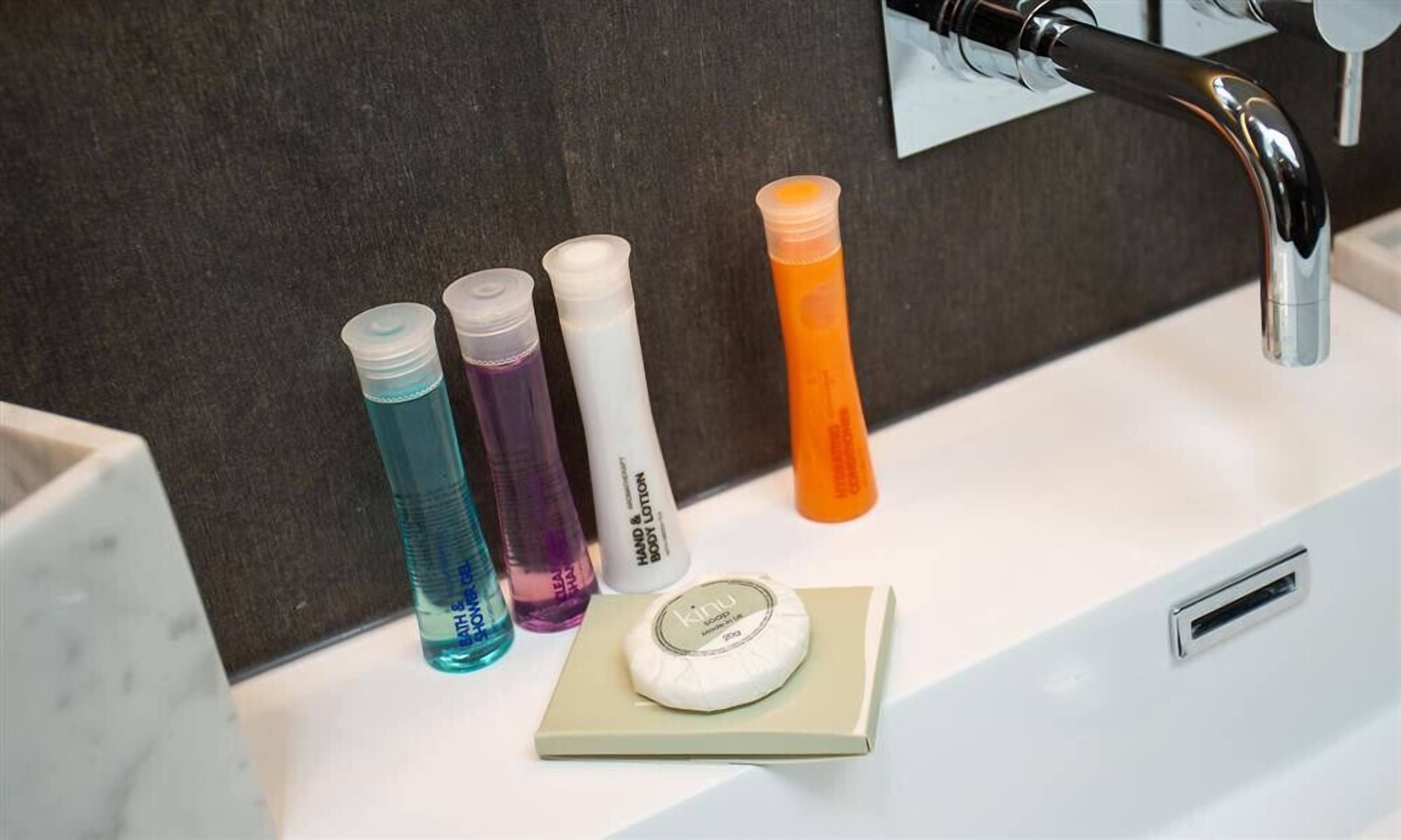 Un lavabo de salle de bain avec quatre bouteilles de savon liquide et un pain de savon.