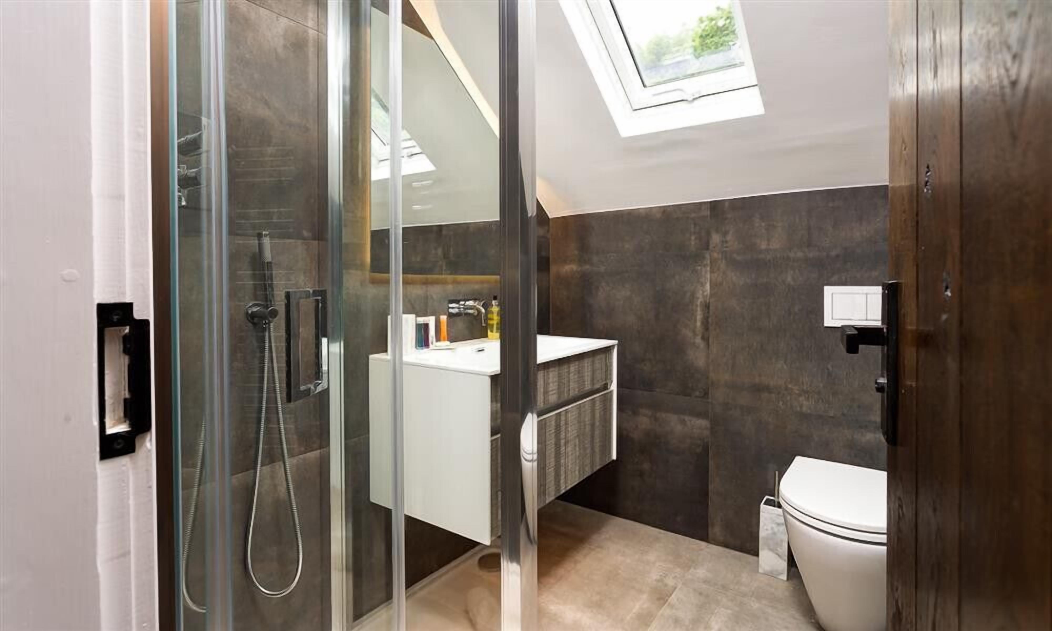 Ein modernes Badezimmer mit Duschkabine aus Glas, einem weißen Waschbecken und einer Toilette.