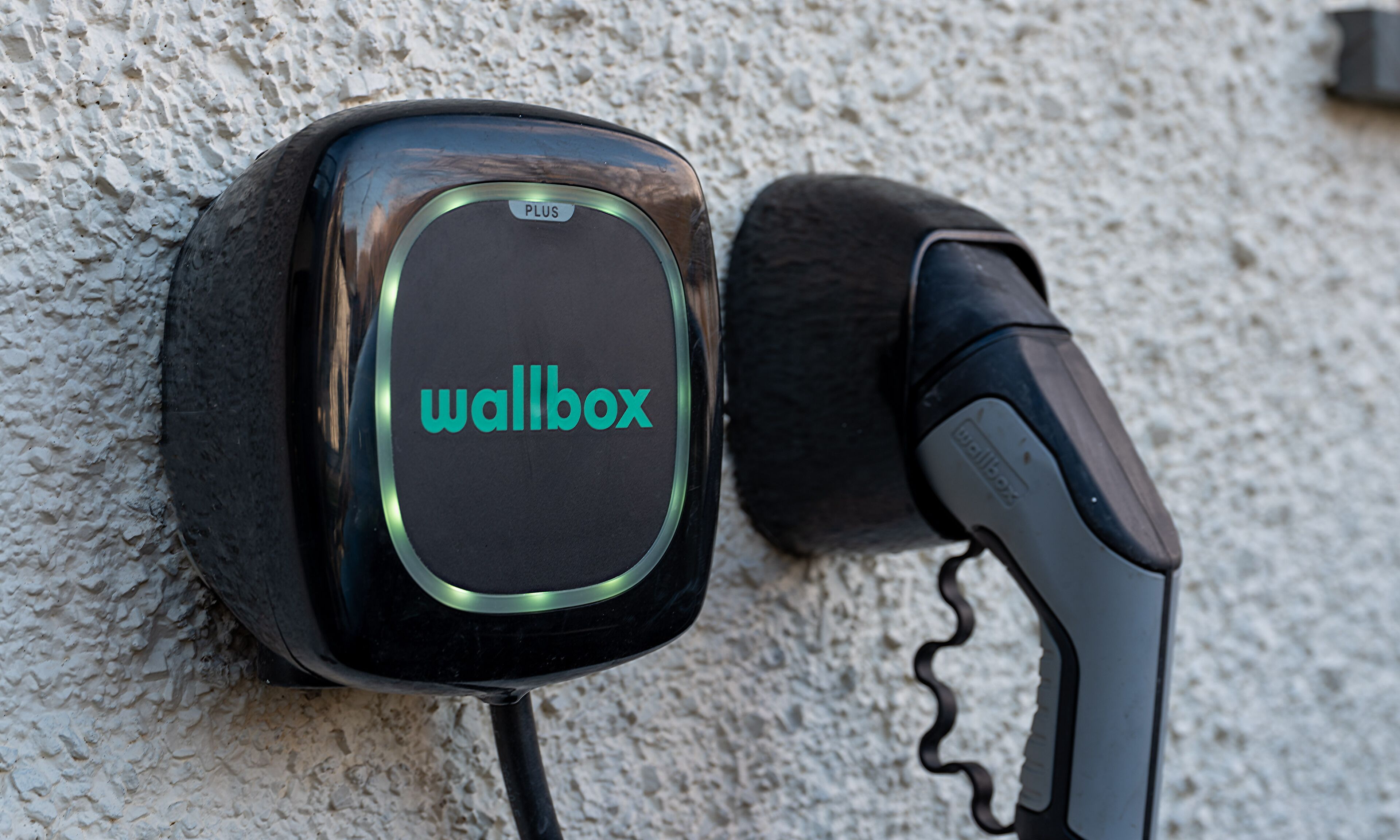 En vægmonteret enhed med ordet "wallbox" på sig, tilsluttet et kabel.