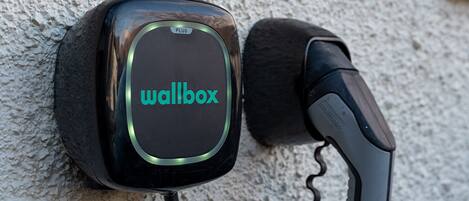 En vægmonteret enhed med ordet "wallbox" på sig, tilsluttet et kabel.