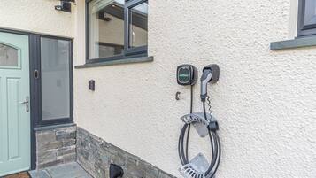 Une borne de recharge pour véhicules électriques, fixée au mur, dotée d’un câble et d’une boîte de contrôle étiquetée « wallbox ».
