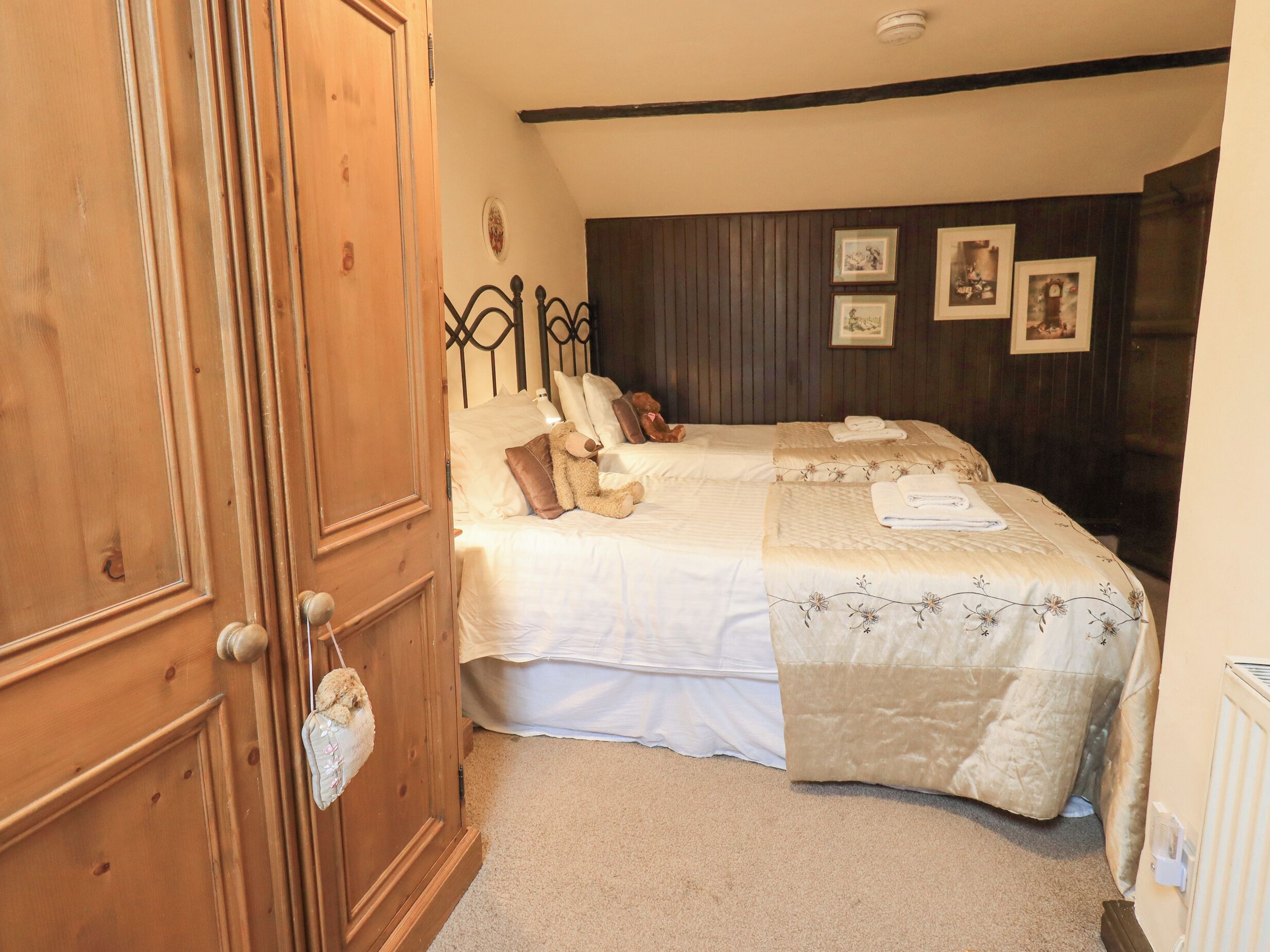 Une chambre avec deux lits, une porte en bois et une tête de lit en bois foncé.