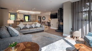 A modern living room with a sofa, coffee table, and a fireplace. - Landower House (Ambleside)