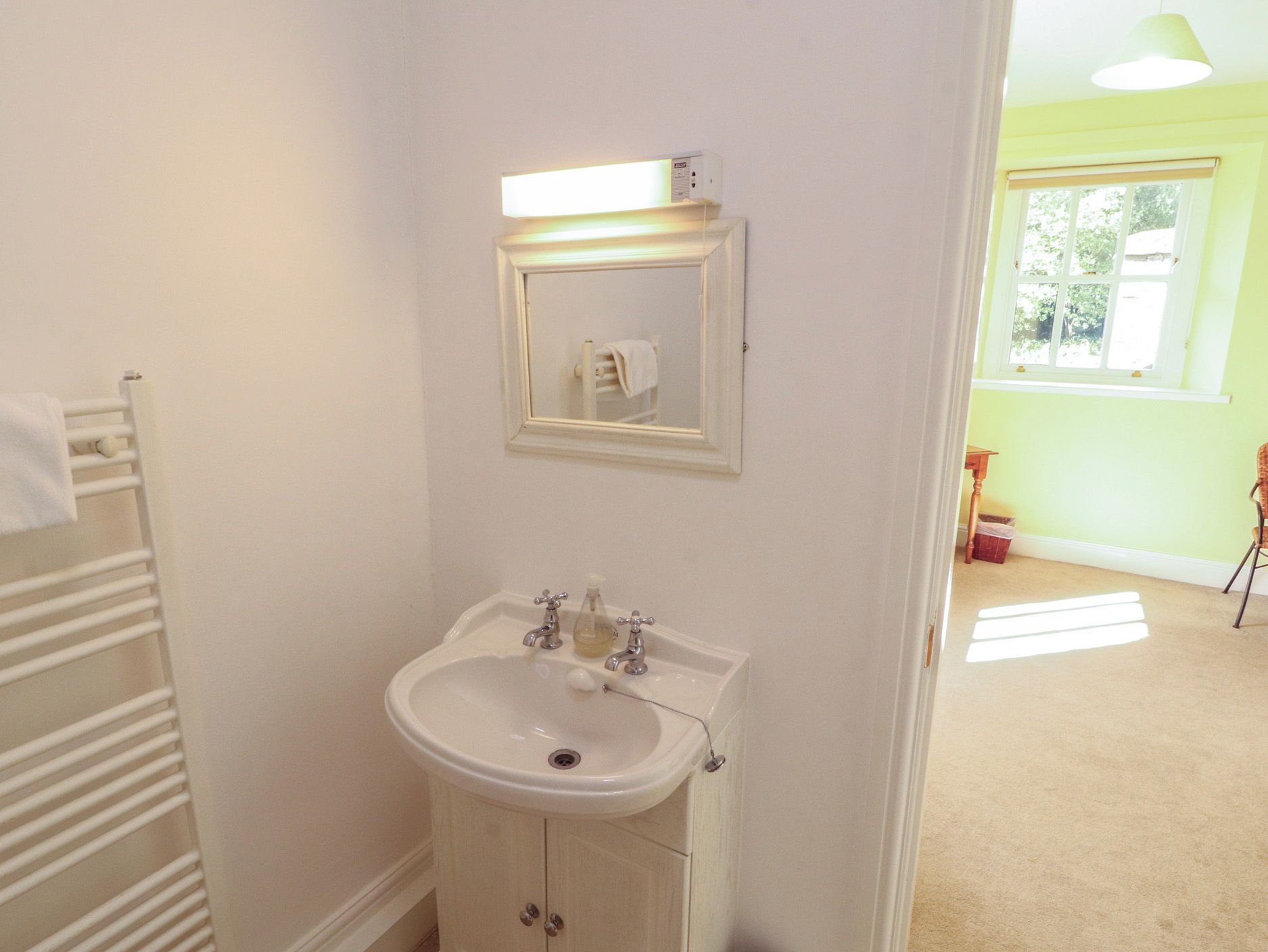 A bathroom with a white sink, a mirror, and a towel rack.