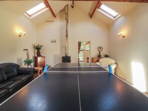 A room with a ping pong table, a fireplace, and a black leather couch. - Hawkshead Hall (Ambleside)