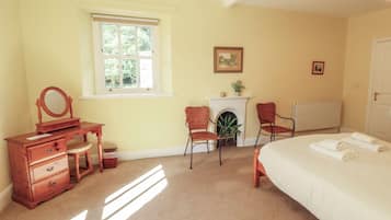 A bedroom with a bed, a dresser, a chair, a fireplace, and a window.