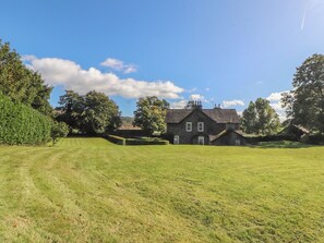 Une grande maison en pierre avec une pelouse bien entretenue à l’avant.