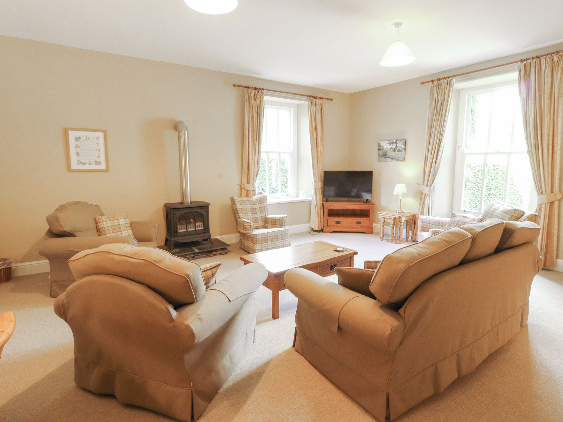 A living room with a sofa set, a television, a fireplace, and a window with curtains.