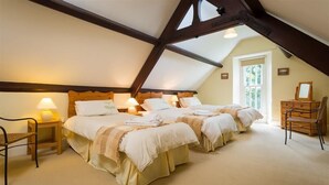Un dormitorio acogedor en el ático con dos camas, cabeceros de madera y un aparador.