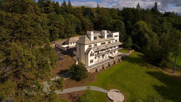 A large, multi-story house with a stone facade, surrounded by lush greenery and a well-maintained lawn. - Hygge at No.8 (Windermere)