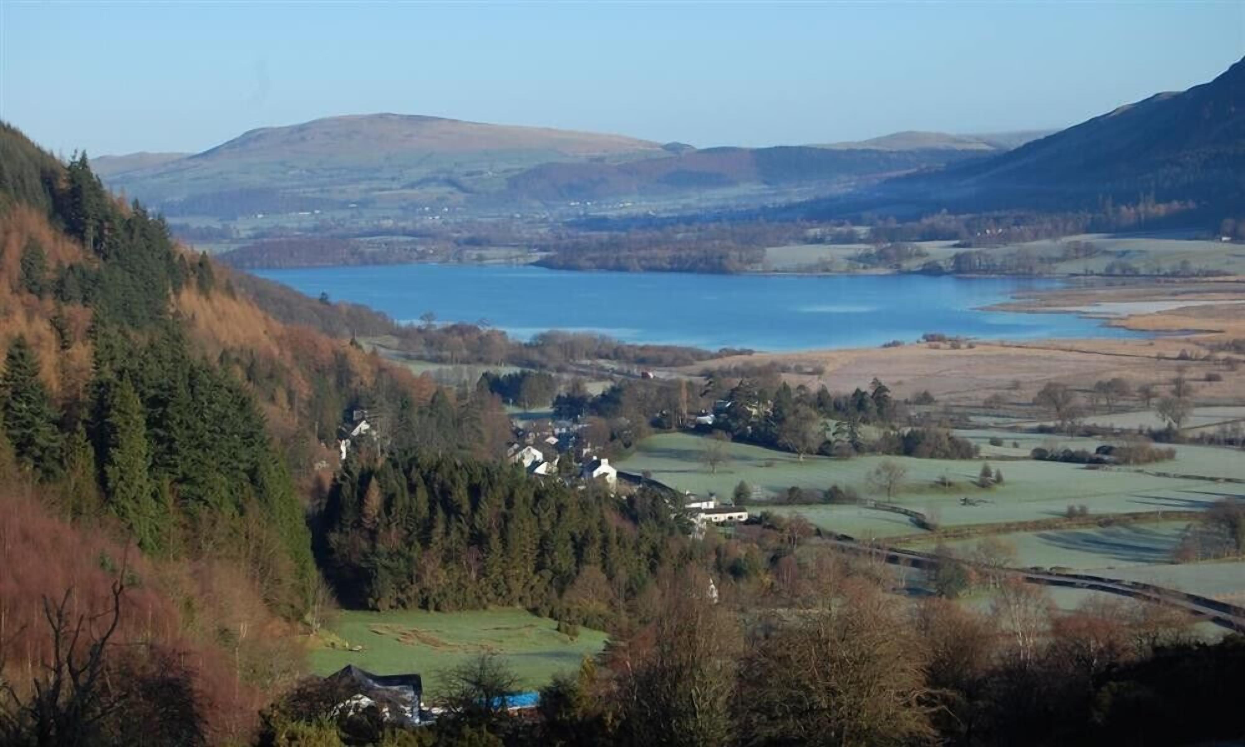 A rural landscape with a lake, rolling hills, and scattered houses.