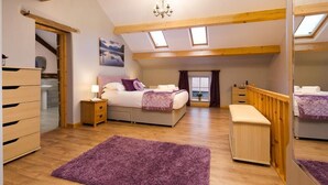 Um quarto com cama, mesas de cabeceira, cómoda, janela e claraboia.