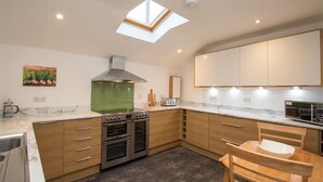 Une cuisine moderne dotée d’une verrière, d’un four encastré et de meubles de rangement en bois.