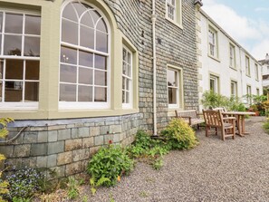 A building with a stone facade, large arched windows, and a gravel driveway.