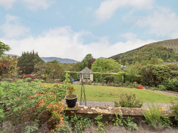 A garden with a small gazebo, a stone wall, and a variety of plants and flowers. - Grisedale View (Keswick)