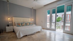 A bedroom with a large bed, a nightstand, a ceiling fan, and a view of the outside balcony. - Beatiful view in front the sea ,inside old City (Cartagena de Indias)