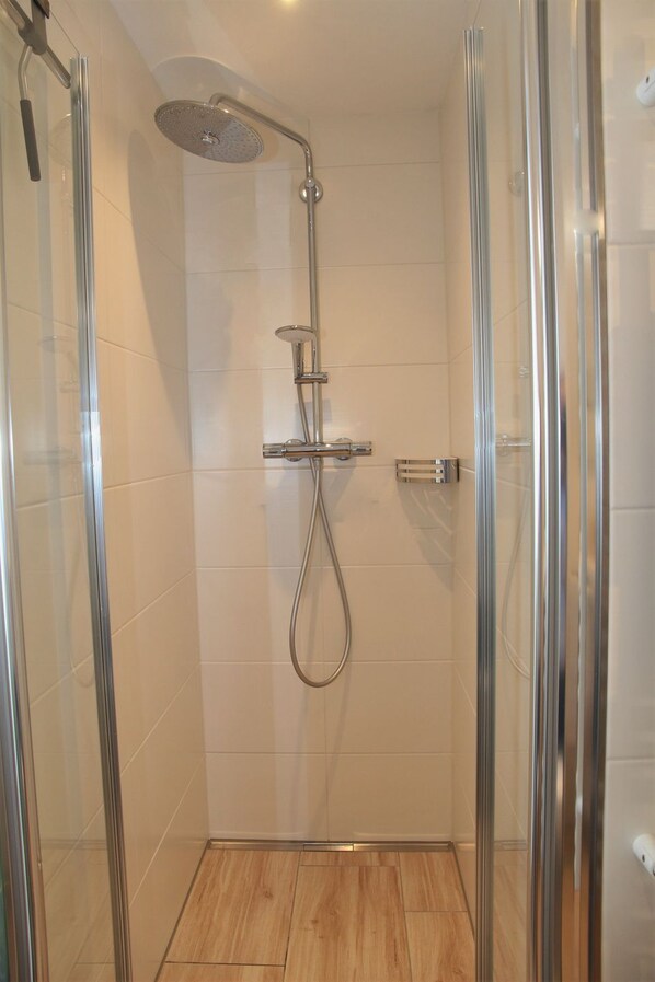 A glass-enclosed shower with a handheld showerhead and a wall-mounted control panel. - Schnack-Stuuv - Great 72sqm apartment for 4 people with terrace in the (Krummhörn)