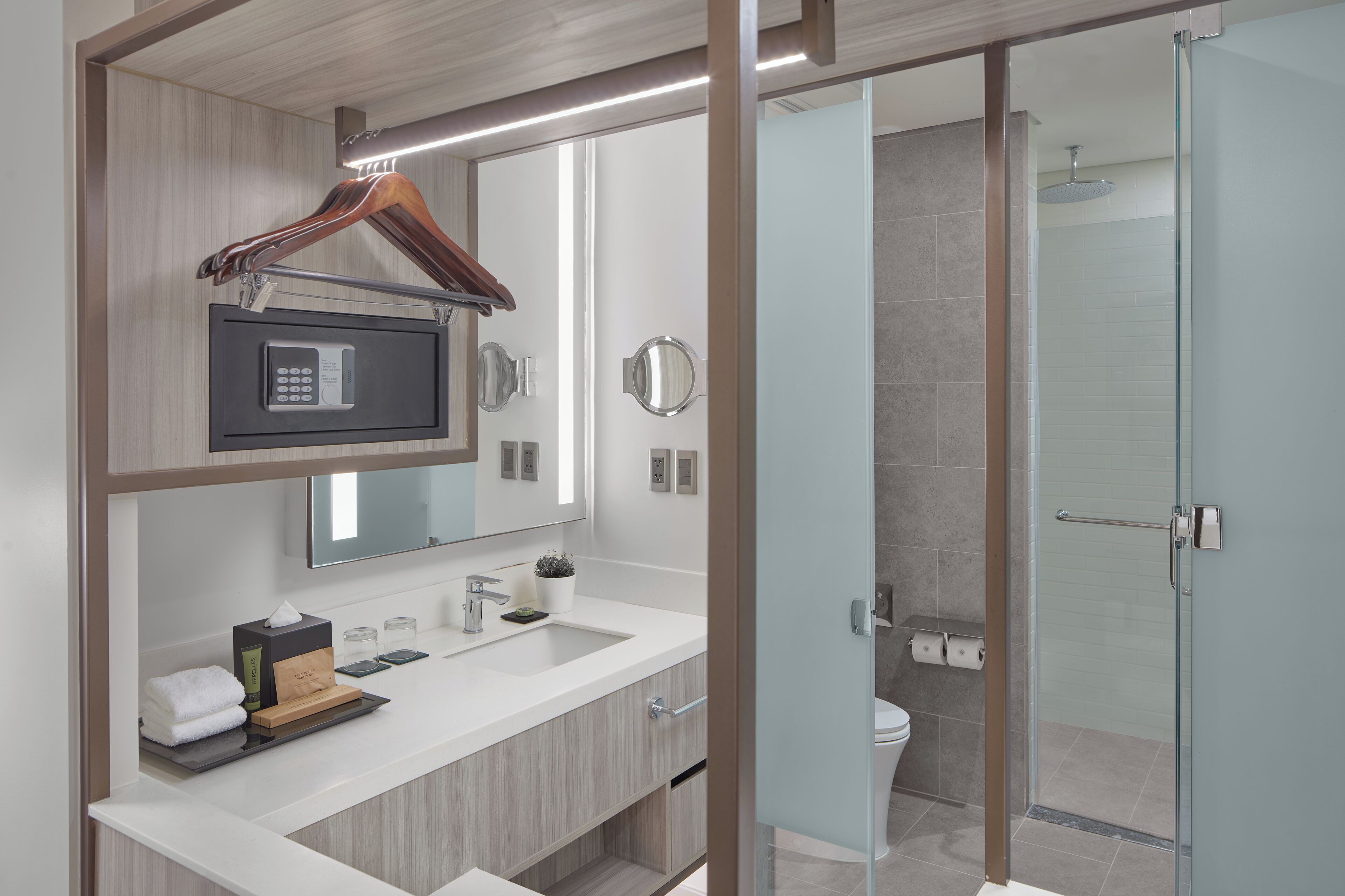 A modern bathroom with a built-in microwave, a large mirror, and a glass shower enclosure.