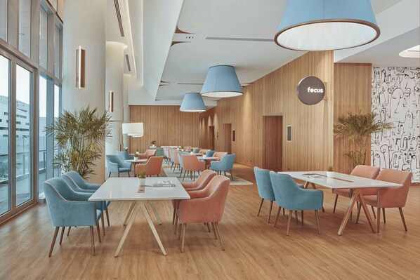 A modern dining area with wooden walls, blue and orange chairs, and large pendant lights. - Lanson Place Mall of Asia Manila (Pasay)