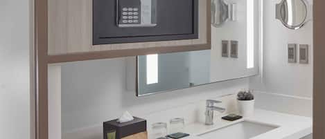 A modern bathroom with a built-in microwave, a large mirror, and a vanity with a sink.