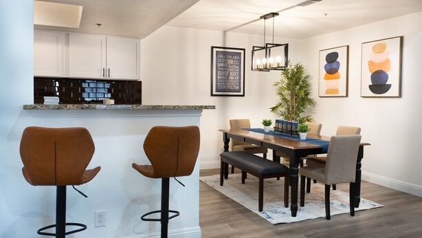 Een moderne keuken met een bar, een eettafel met stoelen en kunstwerken aan de muren.