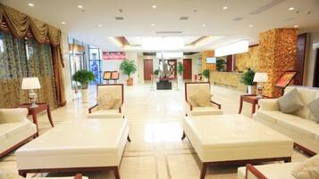 A hotel lobby with seating areas, a reception desk, and a decorative wall.