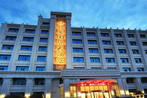 Un edificio de hotel de varios pisos con un cartel vertical llamativo que muestra el nombre del hotel.