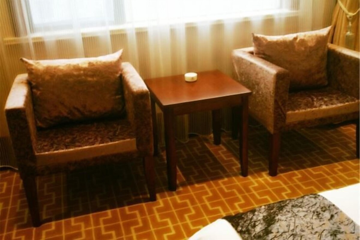 Et hotelværelse med to lænestole, et lille bord og et gulv med et mønster.