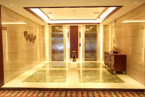 A modern elevator lobby with marble flooring, a central elevator, and a decorative console on the right. - Fuan International Hotel (Zhuxi)