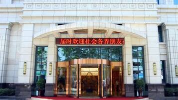 A building entrance with a curved glass door and a red sign above.