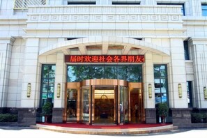 A building entrance with a curved glass door and a red sign above. - Fuan International Hotel (Zhuxi)