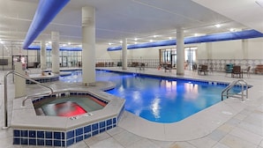 Une piscine intérieure dotée d’un jacuzzi, d’un espace détente et d’un plafond transparent.