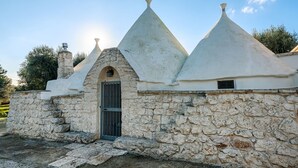 A stone building with a central arched entrance and conical roofs. - Trullo Delle Ginestre Private Pool, Latiano, Italy (Latiano)