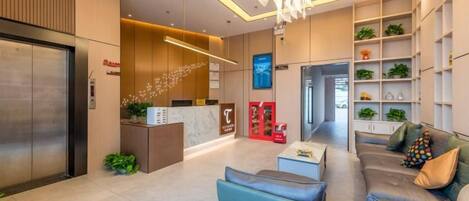 A modern hotel lobby with a reception desk, seating area, and a reception counter.