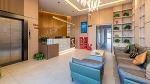A modern hotel lobby with a reception desk, seating area, and a staircase leading to an upper floor. - Taoyuan Hotel (Foshan Guanyao Branch) (Foshan)