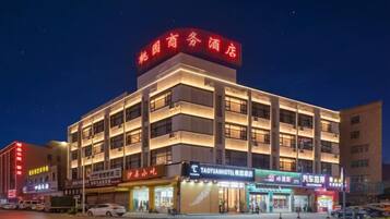 A multi-story hotel with illuminated signage, a ground-level restaurant, and a visible entrance.