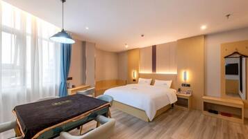 Una habitación de hotel con cama, mesitas de noche, un escritorio con silla, una lámpara colgante y un armario.
