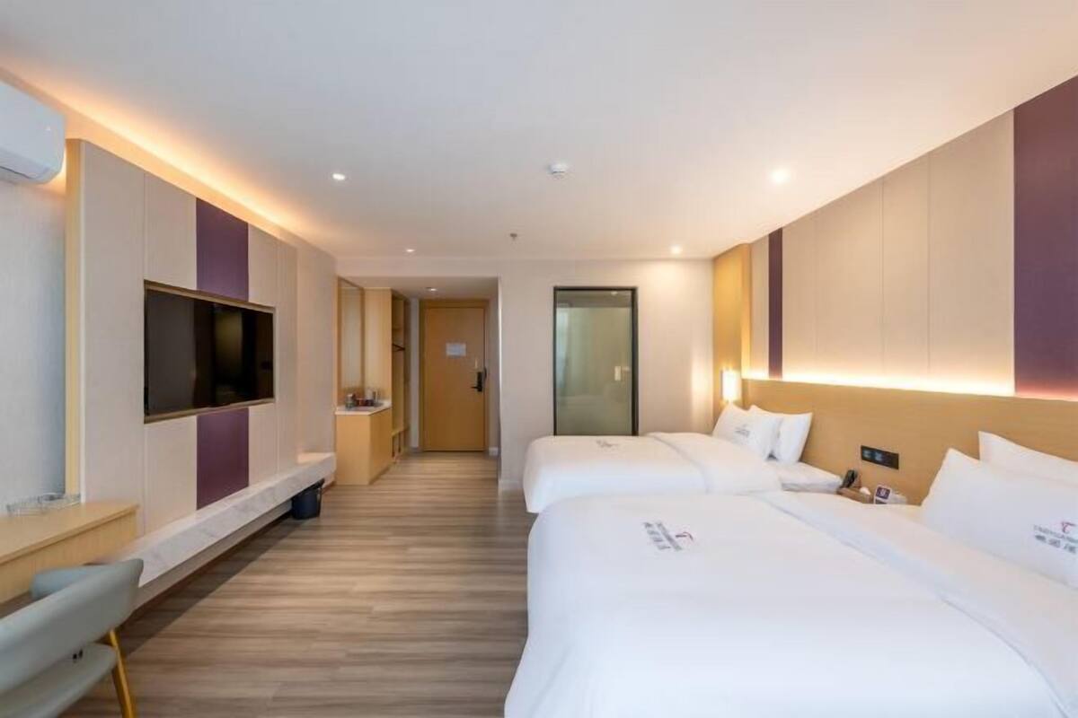 Two single beds with white linens, flat-screen TV, and bedside table.