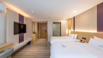 A hotel room with two beds, a TV, a desk, and a bathroom door.