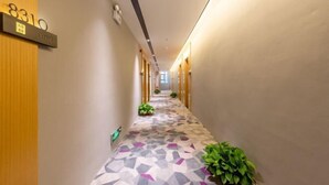 A hallway with a geometric patterned floor, a sign with the number 8310, and potted plants along the walls. - Taoyuan Hotel (Foshan Guanyao Branch) (Foshan)