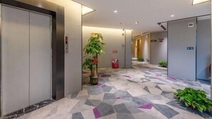 A modern hallway with elevators, potted plants, and a patterned floor. - Taoyuan Hotel (Foshan Guanyao Branch) (Foshan)