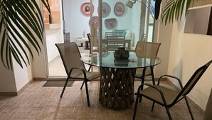 A glass-top dining table with four chairs, a decorative centerpiece, and a tiled floor. - CONDO GAVIOTAS II DEP 105 (Playa del Carmen)