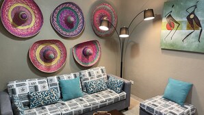 A living room with a grey sofa and ottoman, patterned cushions, a wooden coffee table, and a floor lamp. - CONDO GAVIOTAS II DEP 105 (Playa del Carmen)