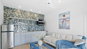 Een moderne keuken met een betegelde spatwand, een witte bank en een schilderij van een strandgezicht.