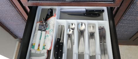 Eine Schublade mit ordentlich angeordneten Küchenutensilien, darunter Messer, Löffel und Gabeln.