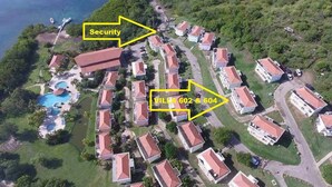 Luchtbeeld van een woongebied met huizen, een zwembad en een beveiligingscomplex.